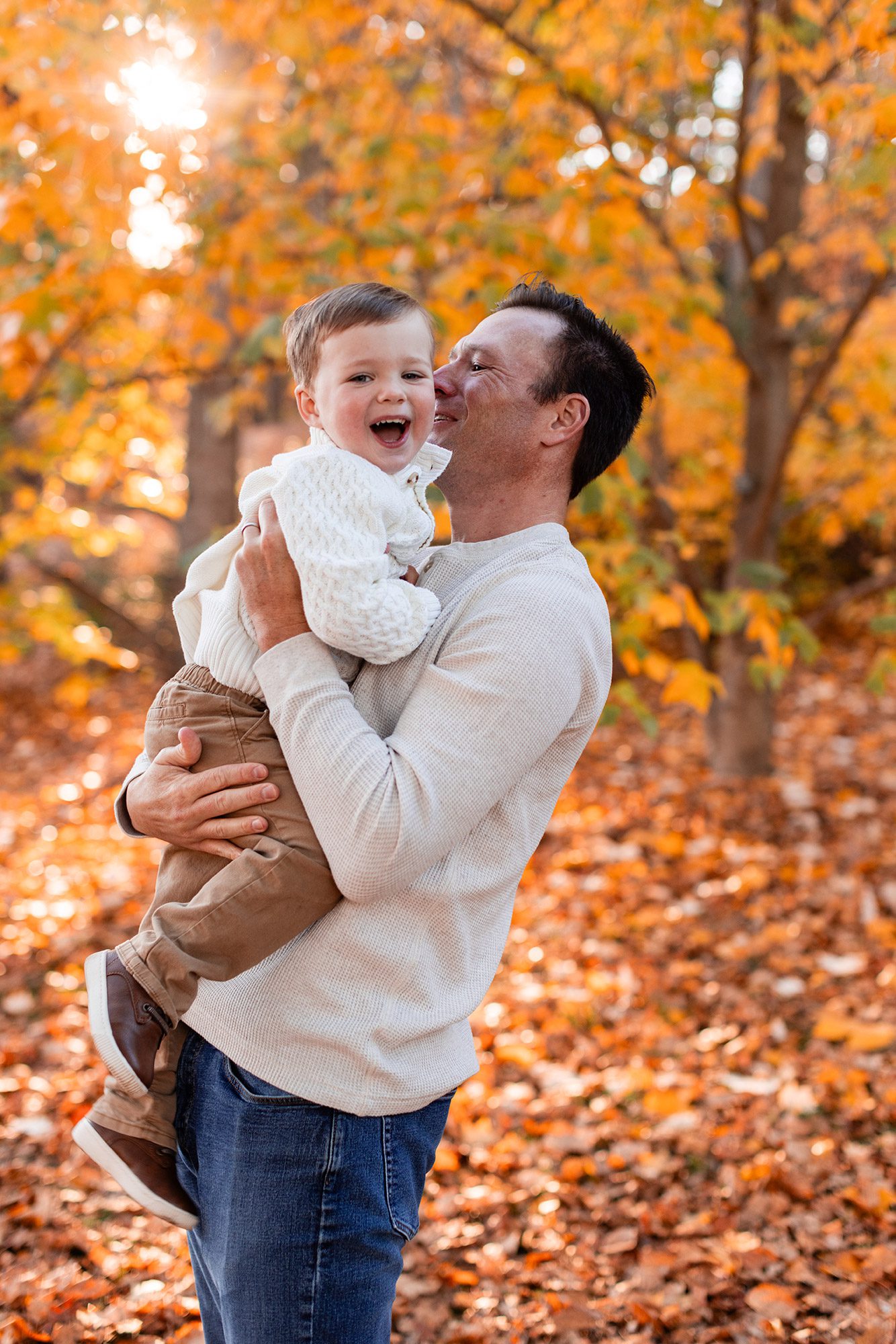 Boston Fall Family Photos - dad in the turning leaves kissing toddler