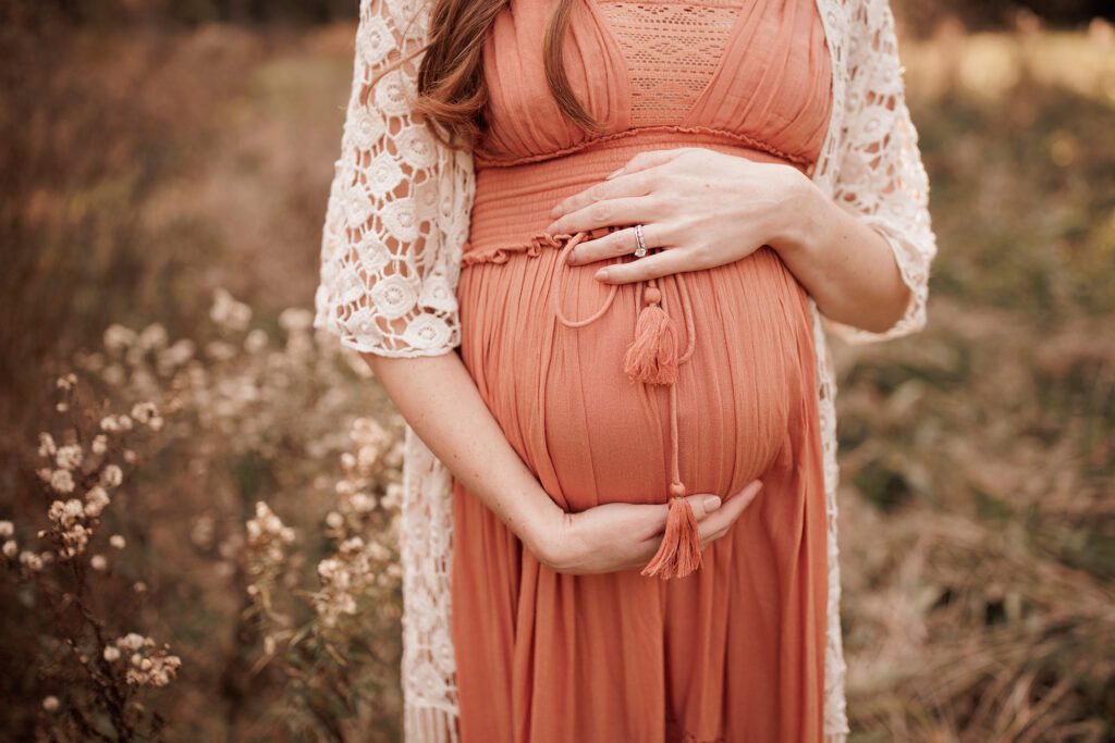 what to wear for your maternity photo session - flowy dress with lace robe over it and flowers in the background