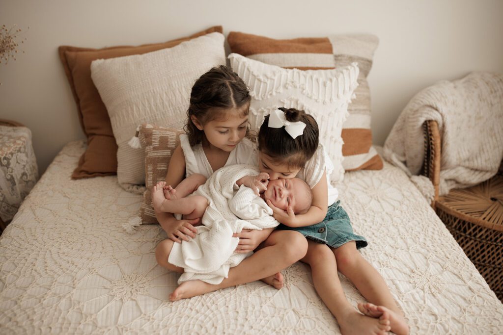 Best Newborn Photos of 2023 baby with two big sisters