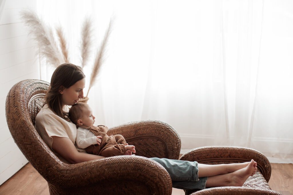 Is my baby too old for newborn photos - mom sitting in a lounge chair holding baby