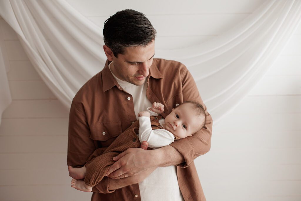 Is my baby too old for newborn photos - baby in dad's arms with a white background