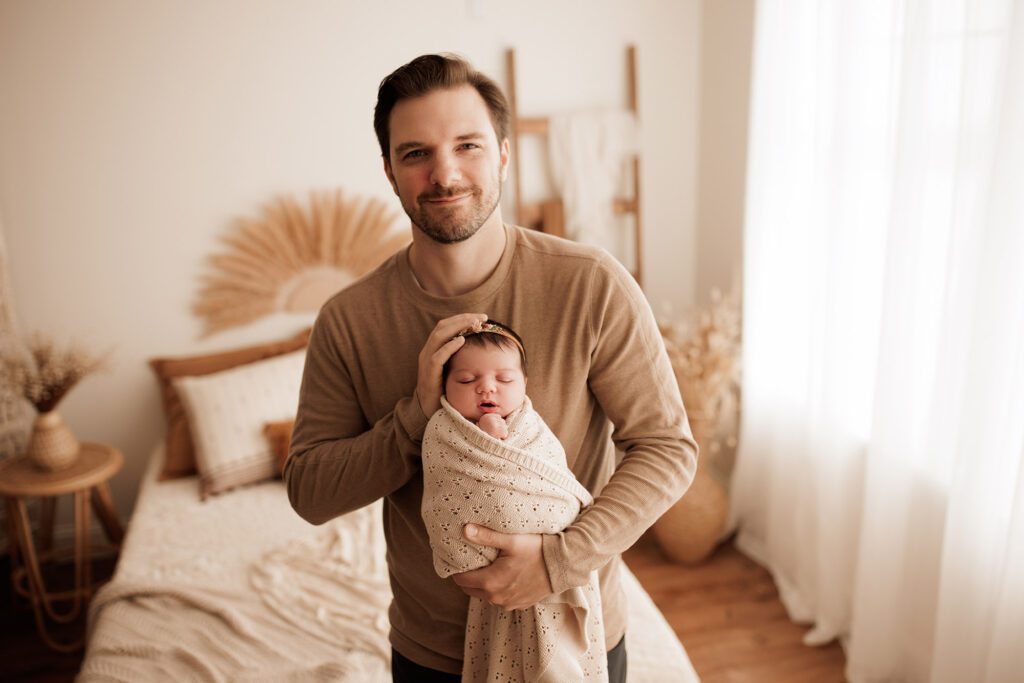 Which type of newborn photo session is best - baby girl swaddled while dad holds her