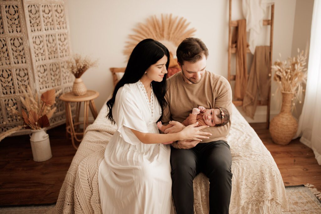 Which type of newborn photo session is best - parents holding baby in a bed neutral studio