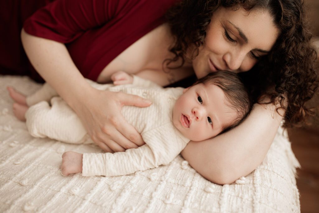 Boston newborn portraits - mom laying with baby giving kisses to his head