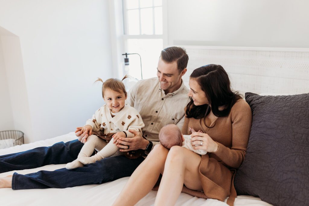 How old should my baby be for newborn photos? - family sitting together with newborn baby