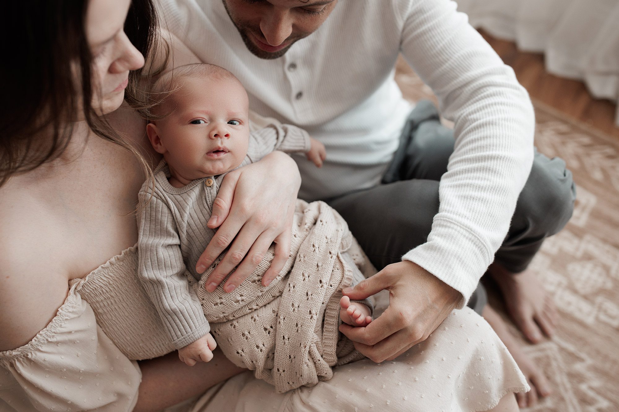 Family Photography with Newborn - baby looking at the camera, dad holding foot