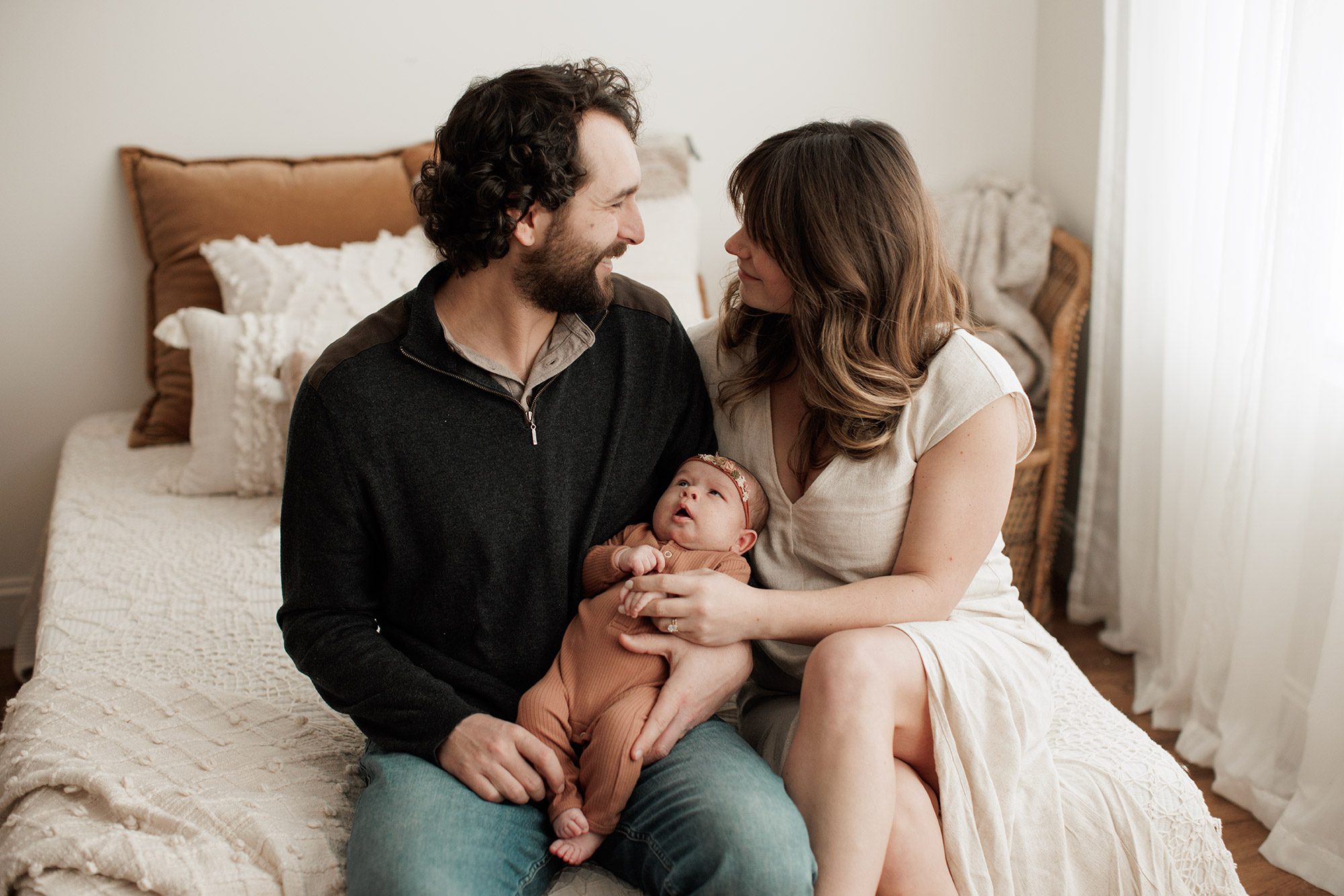 Favorite Newborn Photography Poses - parents sitting together on a bed