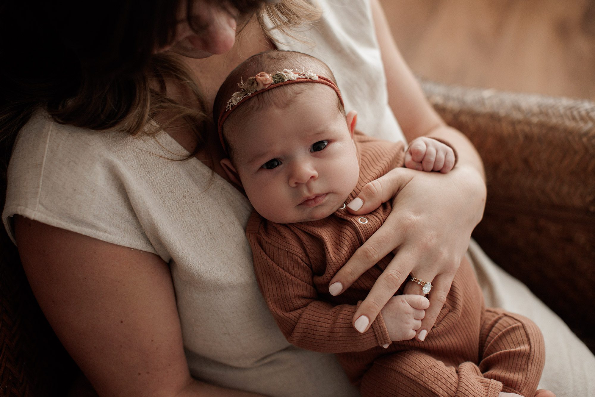 Favorite Newborn Photography Poses - baby girl in looking at the camera in mom's arms