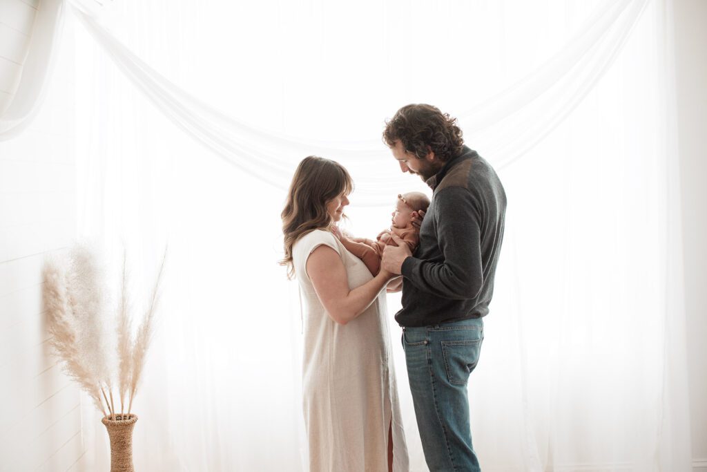Favorite Newborn Photography Poses - couple with baby in front of a big window