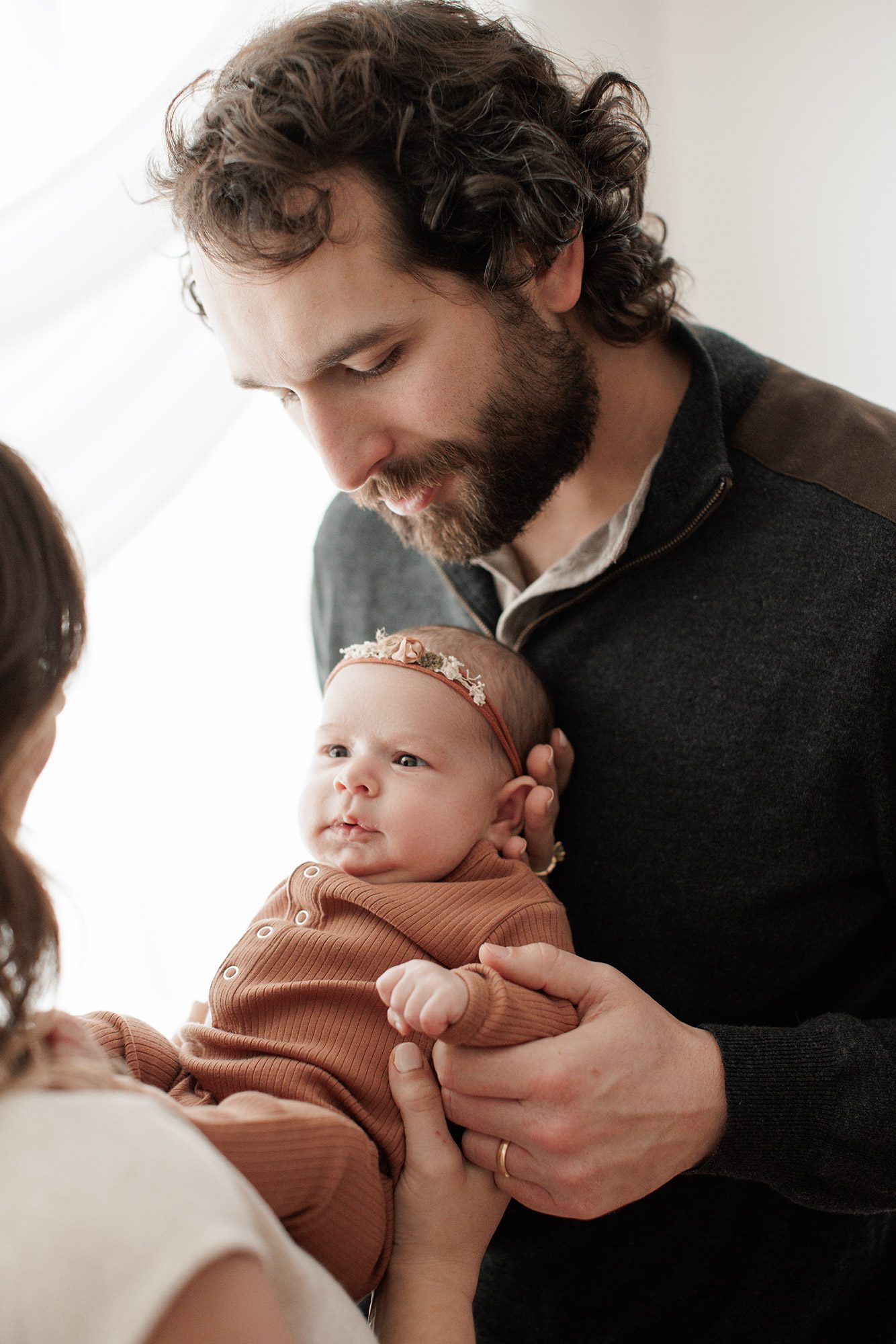 Favorite Newborn Photography Poses - baby in dad's arms in front of a window