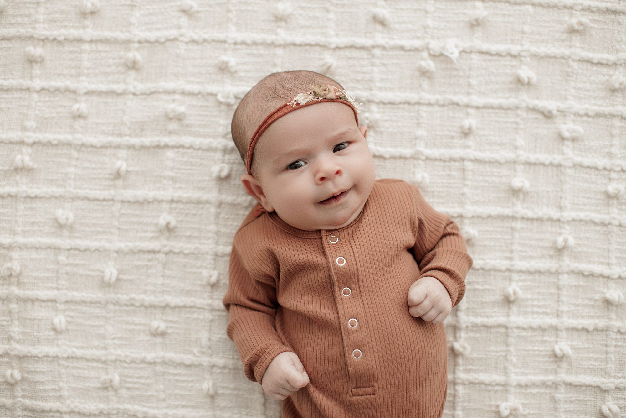 Favorite Newborn Photography Poses - baby girl laying on a bed smiling