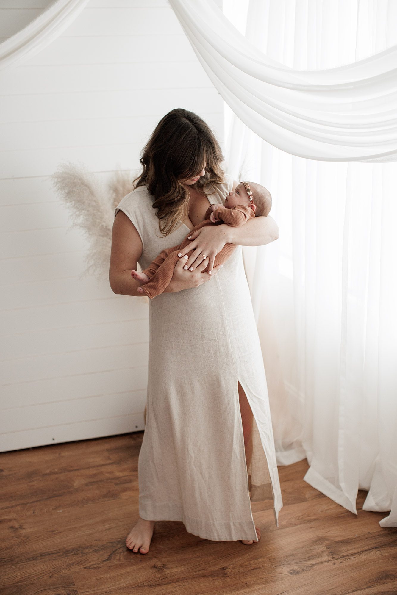 Favorite Newborn Photography Poses - mom holding baby in front of a white wall and window