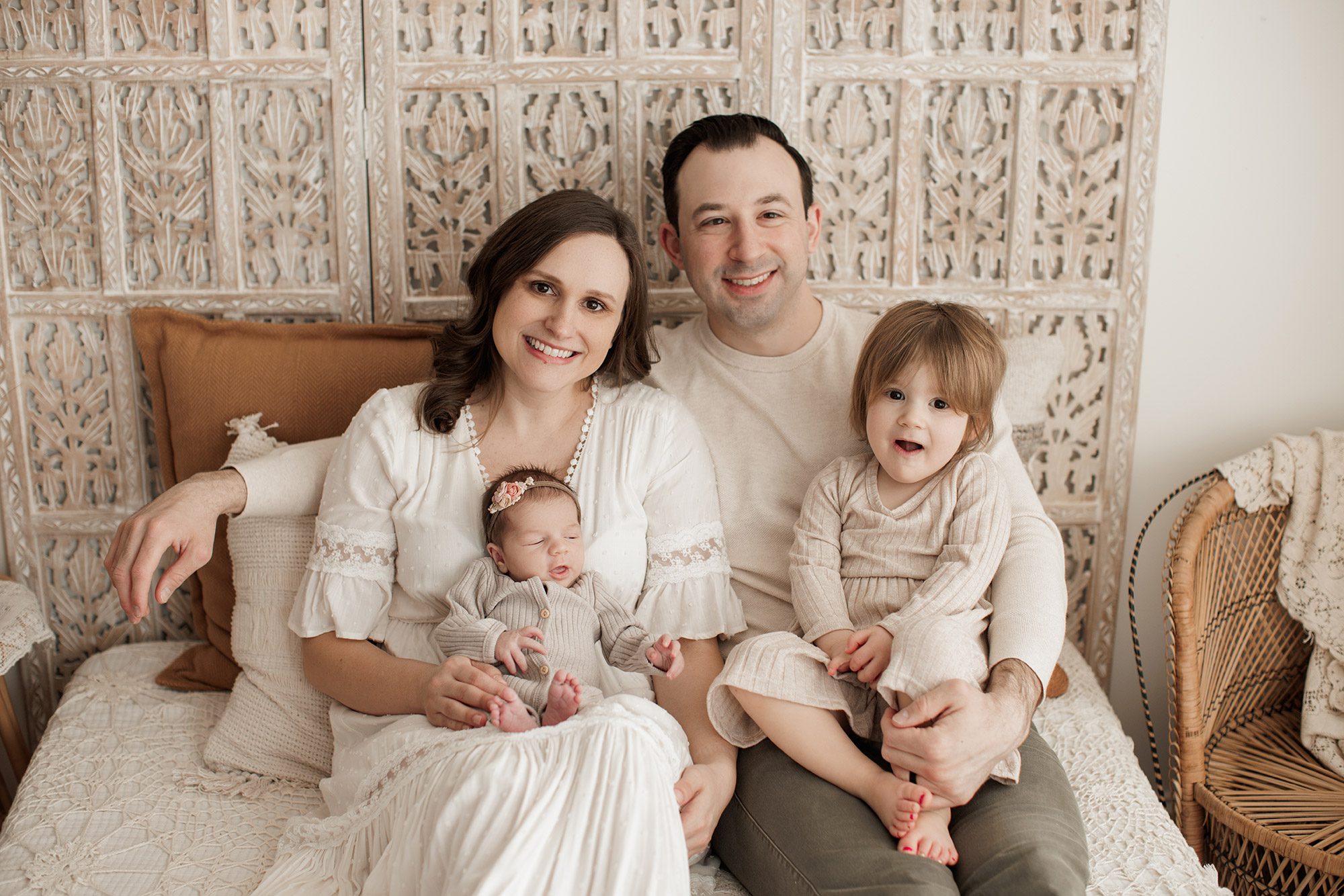 Best Location for a Newborn Photoshoot - family sitting together on a bed white background