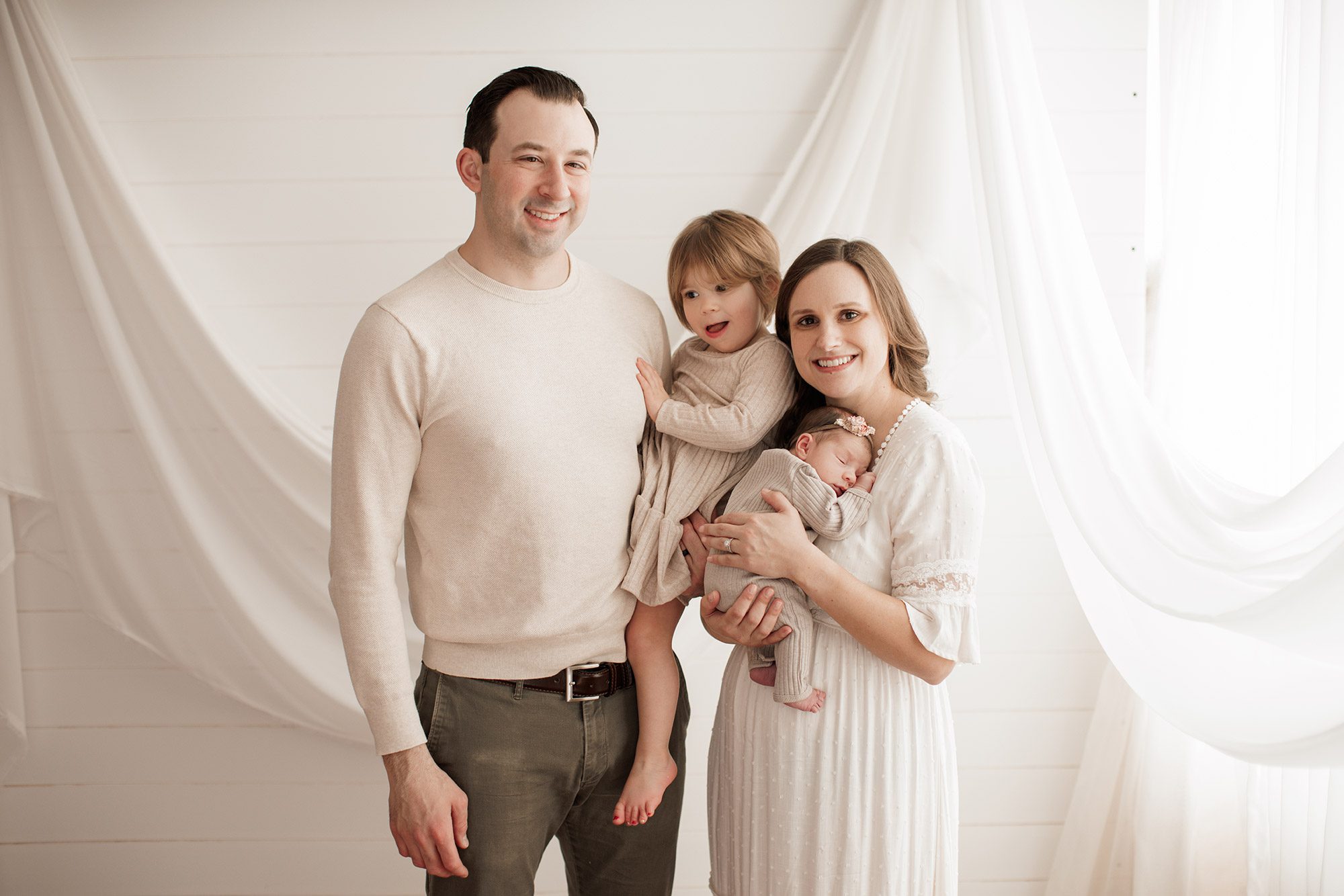 Best Location for a Newborn Photoshoot - neutral colors family in front of white wall