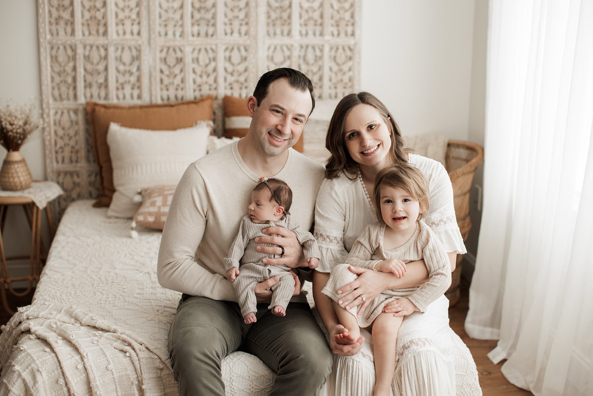 Best Location for a Newborn Photoshoot - family of four sitting on a bed