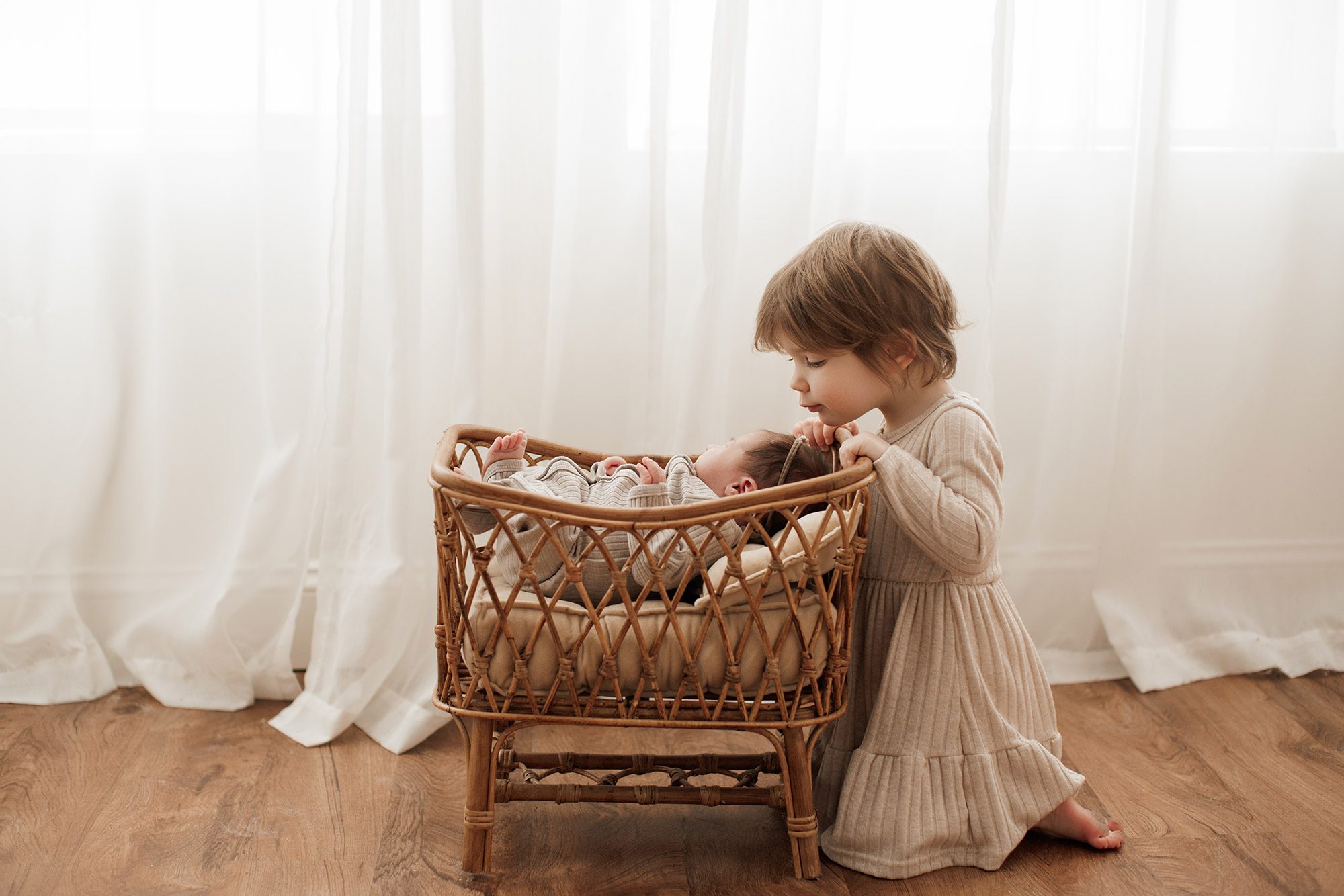 Best Location for a Newborn Photoshoot - big sister looking at baby in a basket