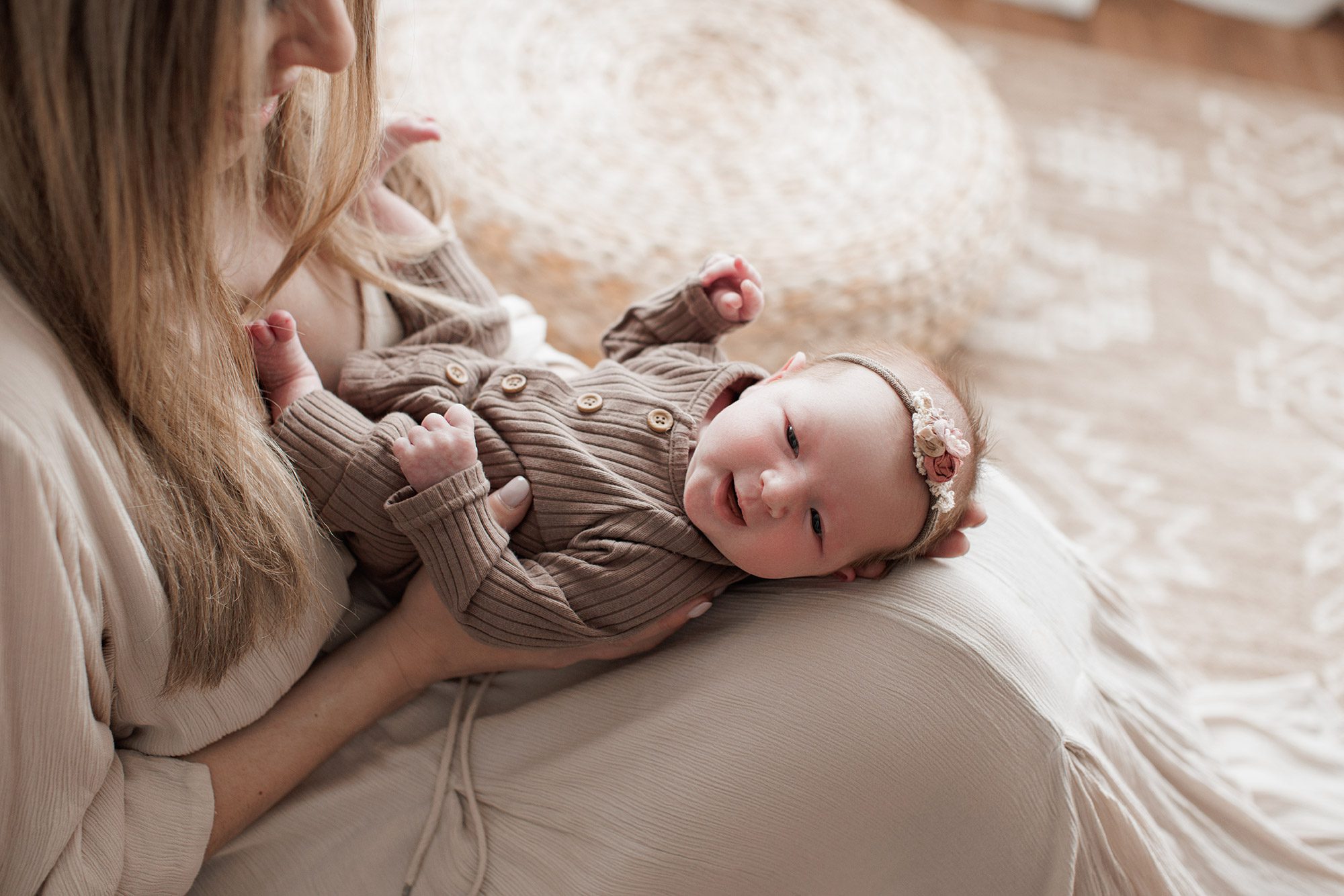 How to choose the right newborn photographer for your family - baby in mom's lap, smiling and looking at the camera