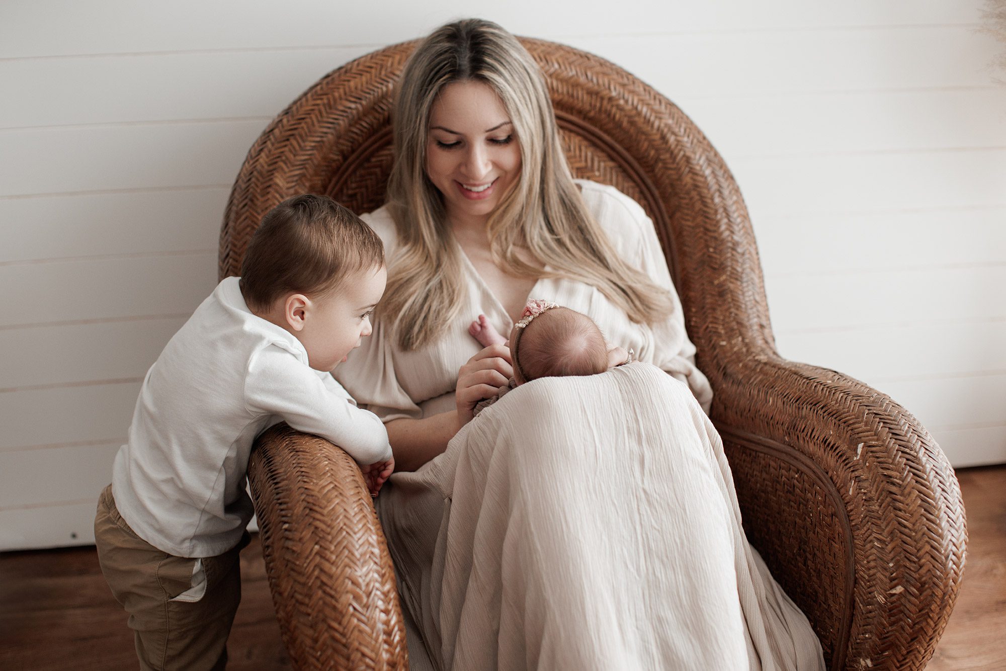 How to choose the right newborn photographer for your family - mom sitting with baby girl and big brother