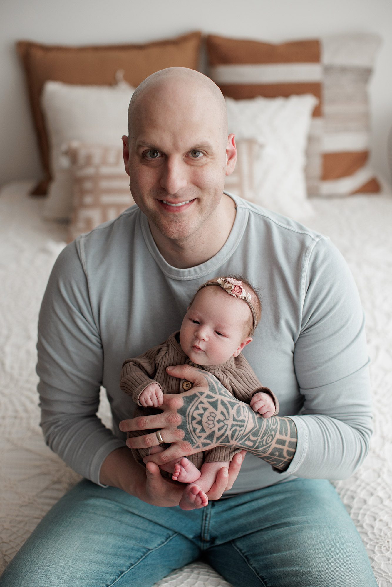 How to choose the right newborn photographer for your family - dad holding baby girl with tattooos