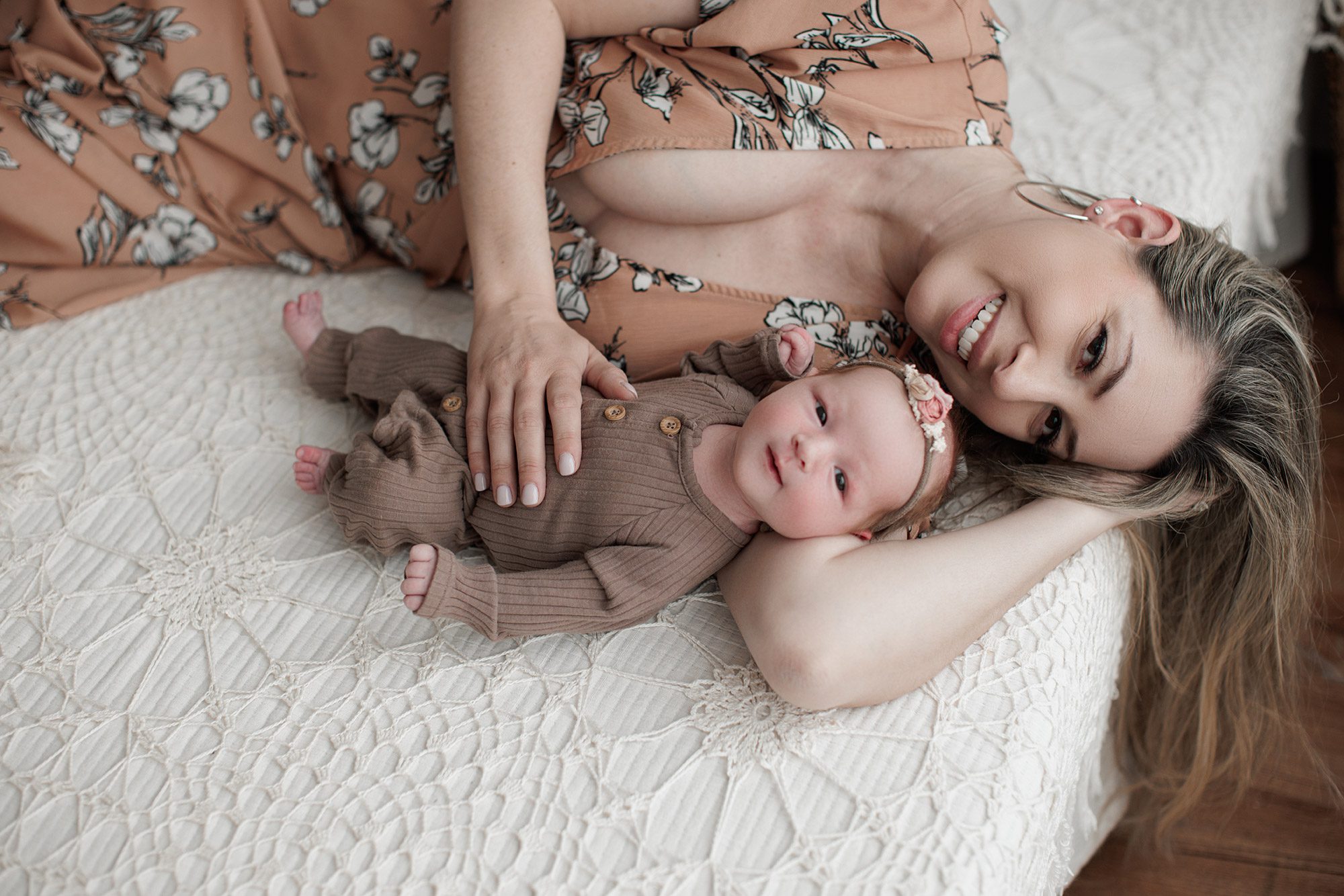How to choose the right newborn photographer for your family - mom laying with baby on a white bed