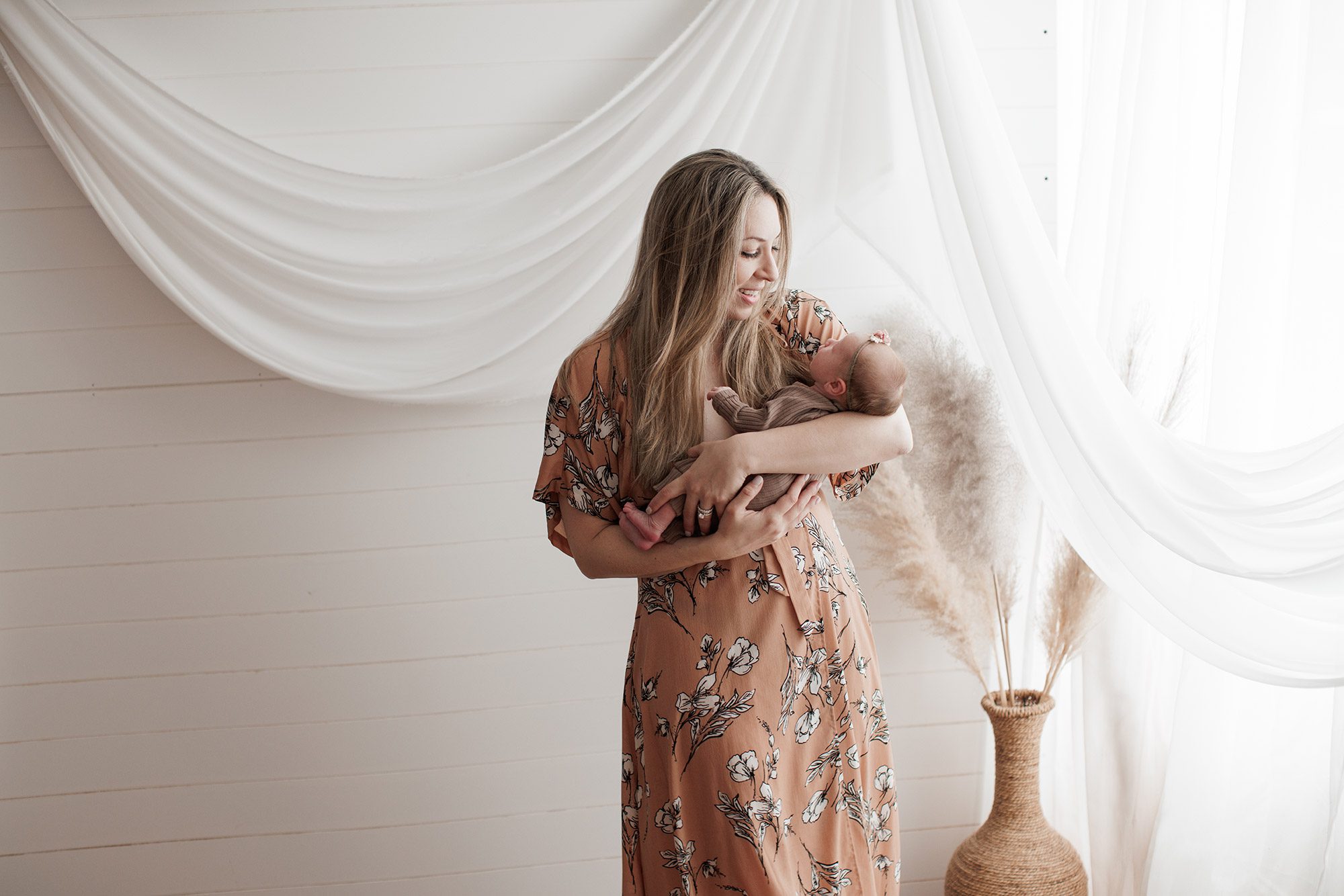 How to choose the right newborn photographer for your family - mom in floral dress holding baby