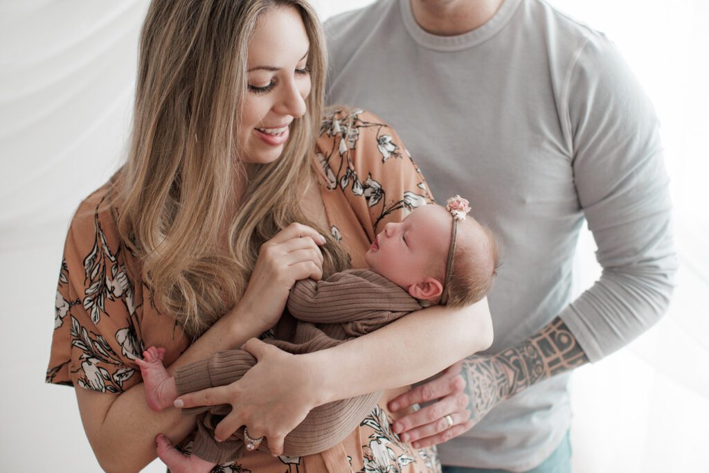 How to choose the right newborn photographer for your family - parents holding baby girl